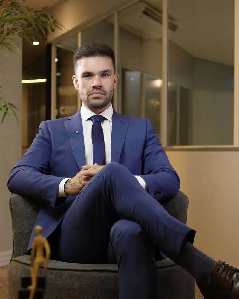 Beto Quintão sentado em poltrona, de terno azul, no escritório da 5G Company