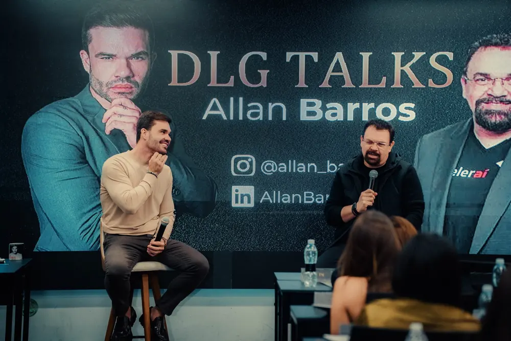Beto Quintão no palco do DLG Talks ao lado do convidado Allan Barros, com a plateia em primeiro plano