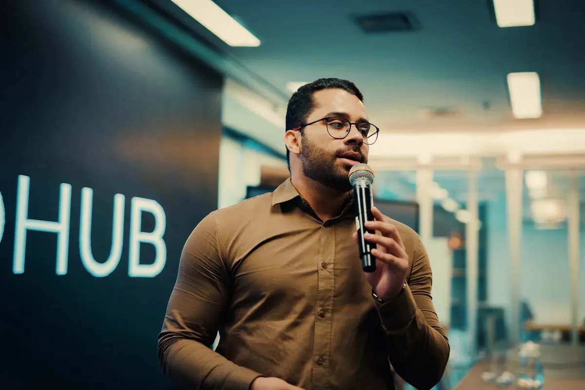 Mentor falando ao microfone em frente ao painel luminoso do MedHub